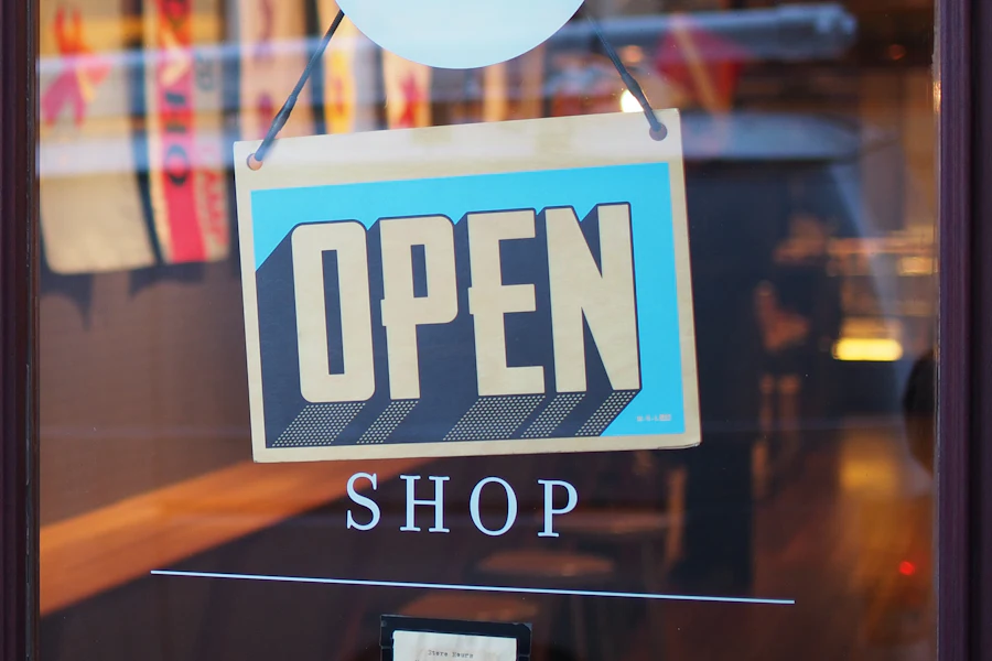 Blue and cream OPEN sign hanging in a shop's glass door above the word SHOP
