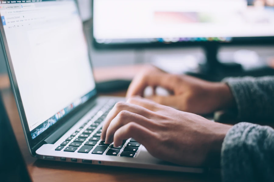 Hands typing on a laptop keyboard while drafting a website brief