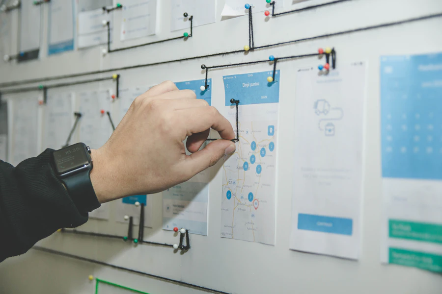 Hand pinning printed page layouts to a wall and linking them into a site map with drawn lines